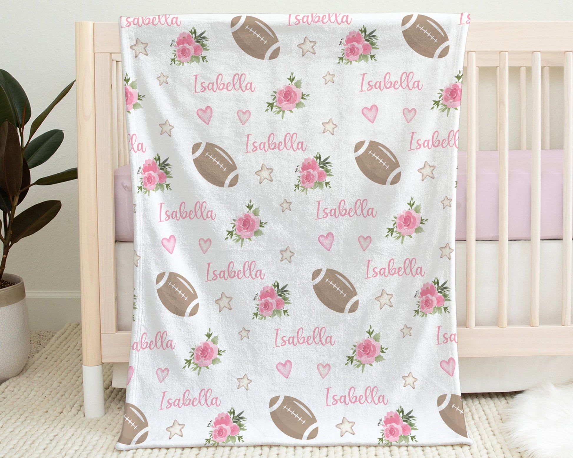 Blanket with footballs and pink flowers and personalized with baby's name in pink.