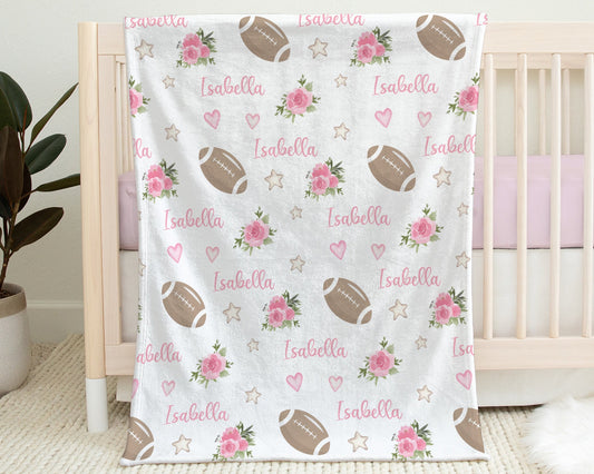 Blanket with footballs and pink flowers and personalized with baby's name in pink.