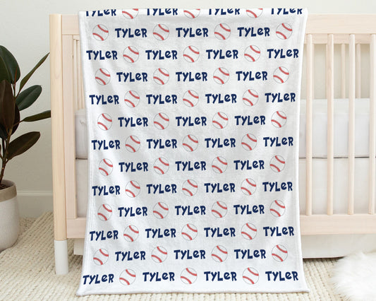 Blanket with baseballs and personalized with baby's name in blue hanging on the side of a crib.