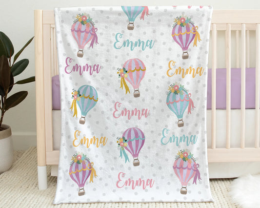 a baby crib with a blanket with hot air balloons on it